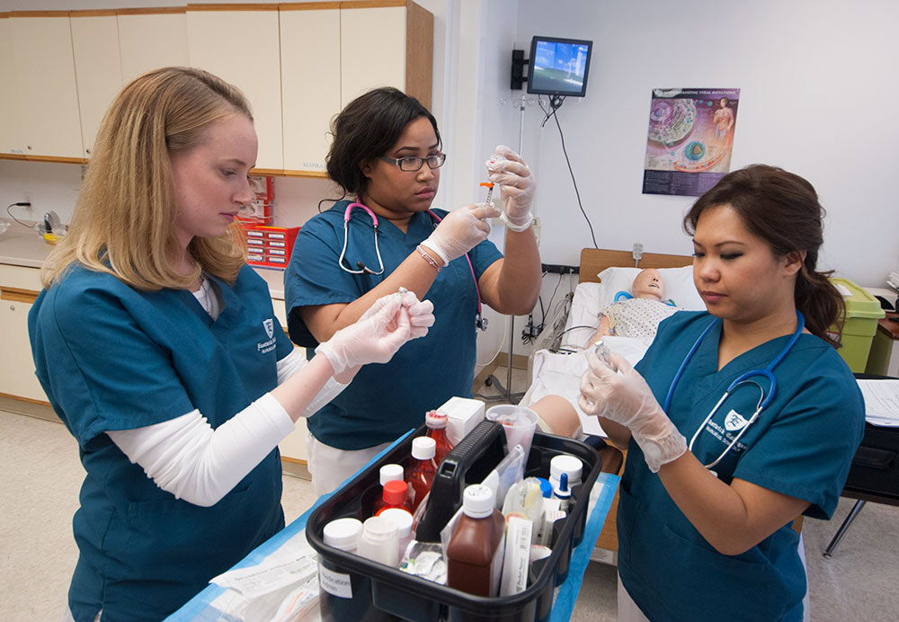 LPN program students practice taking liquid out of bottles using syringes