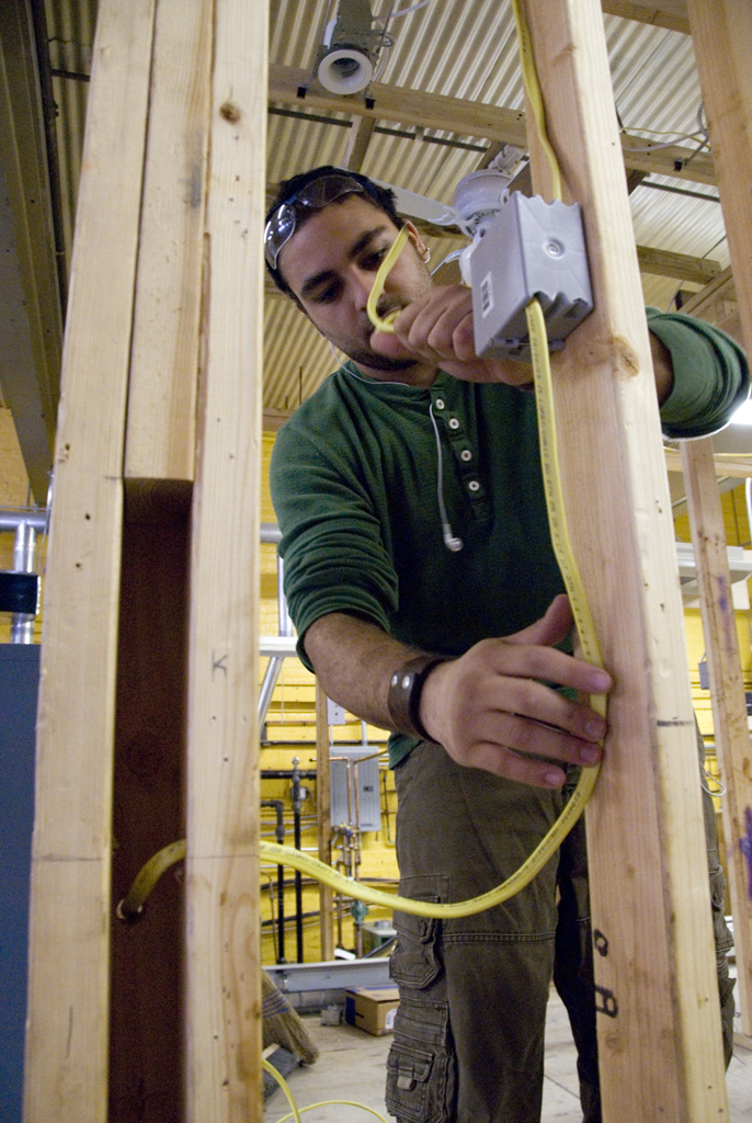 Construction training program student measures beam of wood